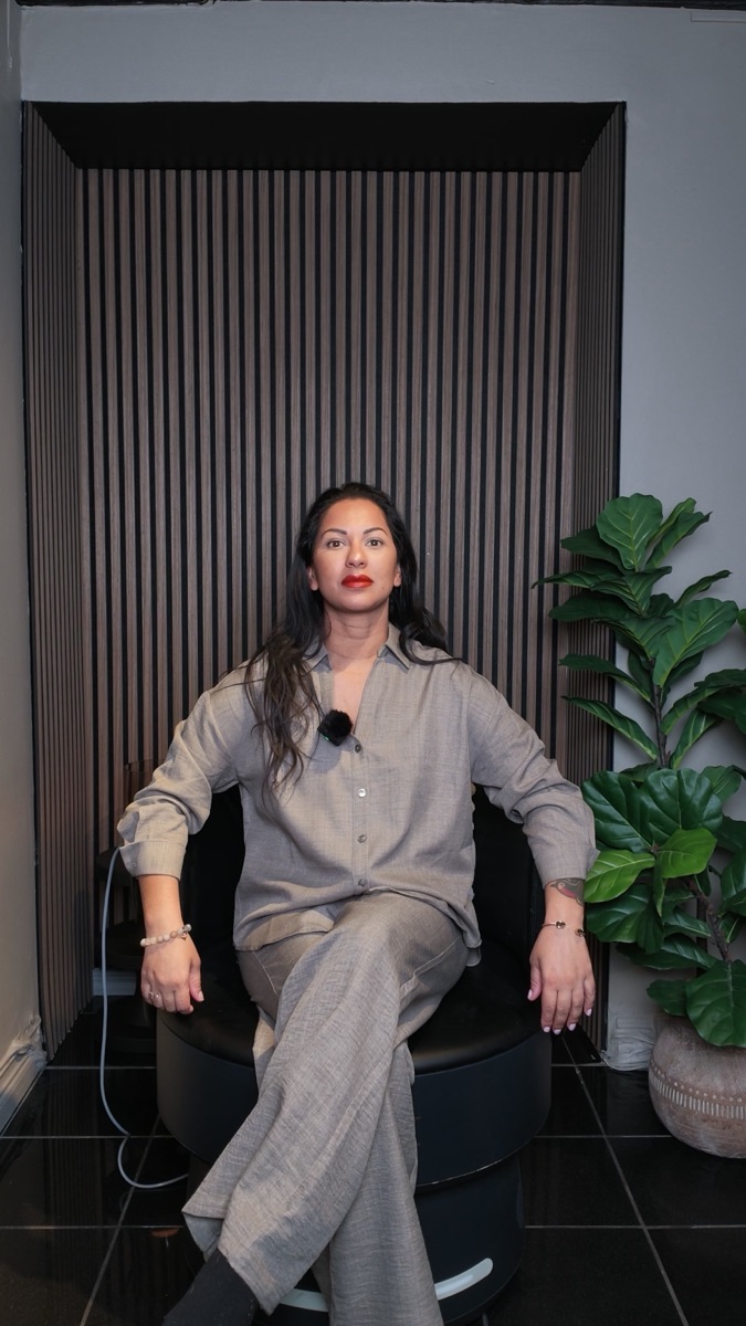 Rosanna Mione sitter fullt påklädd i Insculpt Chair i behandlingsrummet på Studio Mione Clinic i Göteborg